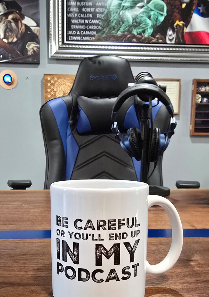 Empty podcast chair in front of a mic. A cup on the table says "be careful or you'll end up in my podcast".